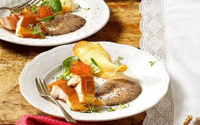 Räucherfisch mit Mohnmayonnaise und Kartoffelchips auf einem weißen Teller angerichtet, dazu gibts noch Lachskaviar und frische Kräuter