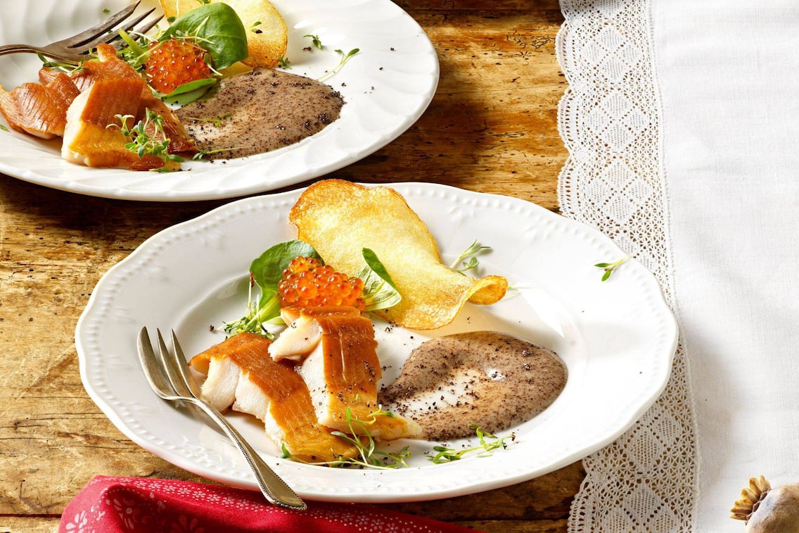 Räucherfisch mit Mohnmayonnaise und Kartoffelchips auf einem weißen Teller angerichtet, dazu gibts noch Lachskaviar und frische Kräuter