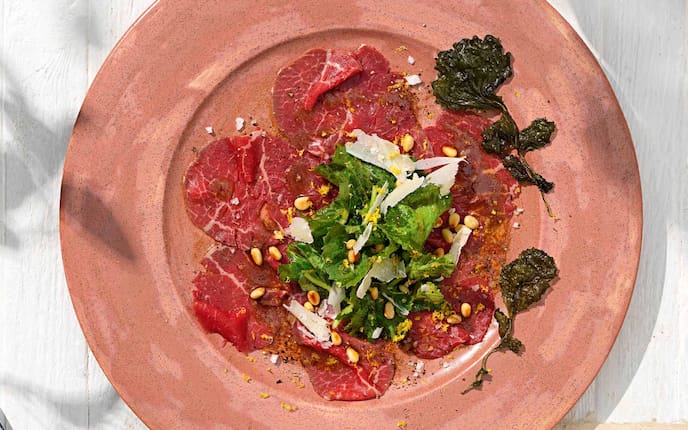 Rinder-Carpaccio mit Rettichblättern, Parmesan, Pfeffer, Salzflocken, Pinienkerne