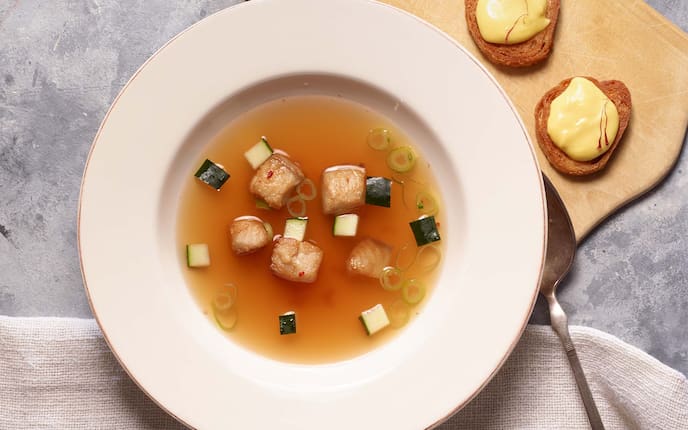 Fischsuppe mit Waller und Safran-Mayonnaise, Baguette, Löffel, Holzbrett, Frühlingszwiebel, Zucchini