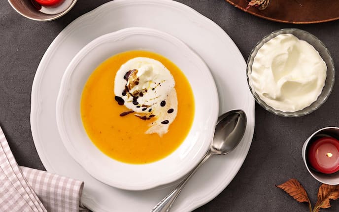 Kürbiscremesuppe, Kerzen, Blätter, Kürbiskernöl, Serviette, Löffel, Schlagobers