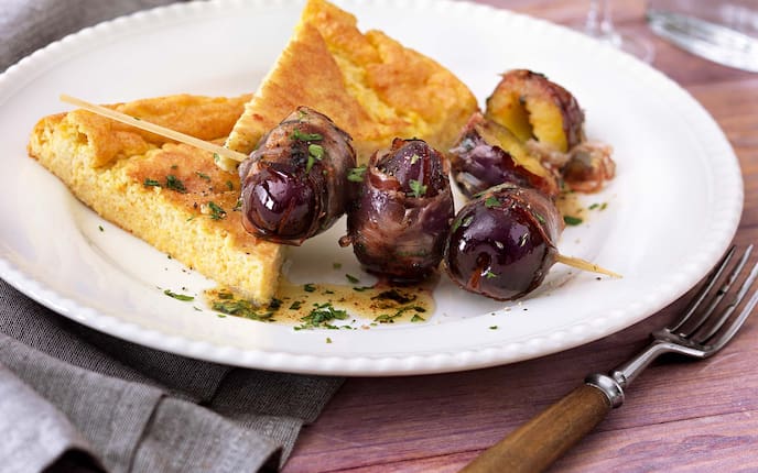 Tiroler Speckzwetschkenspieße mit Polentaschnitten, Gabel, Weinglas, Serviette, Teller