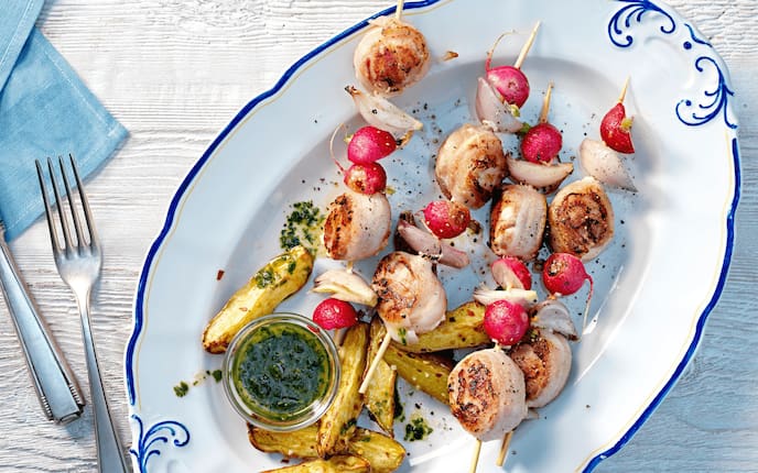 Ziegenkäsespieße im Speckmantel mit Schalotten und Radieschen, Kräuteröl, Teller, Serviette, Holztisch, Ofenerdäpfel