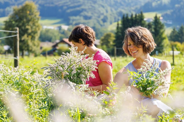 Zwei Frauen pflücken Kräuter in Ruhpolding.